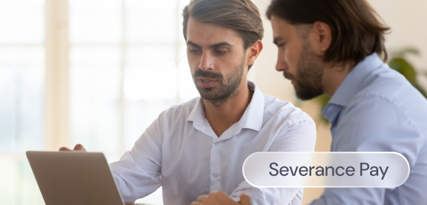 Two men look at a laptop while discussing severance pay