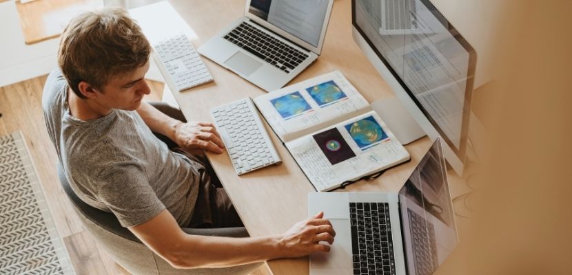 man sitting in front of a computer and laptops