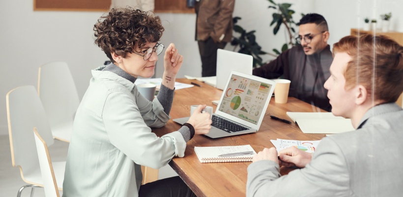 a team of hr managers sat around a computer discussing the new hr software being implemented