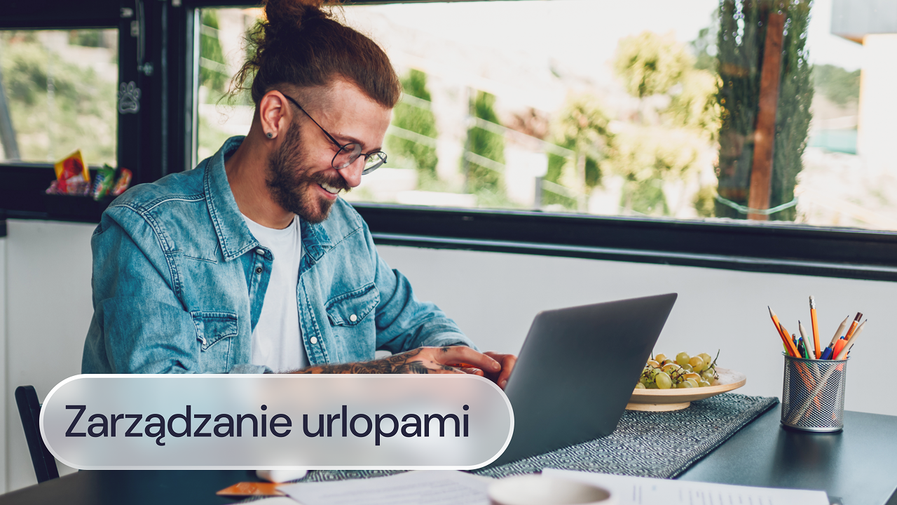 Mężczyzna w okularach pracuje na laptopie przy stole.