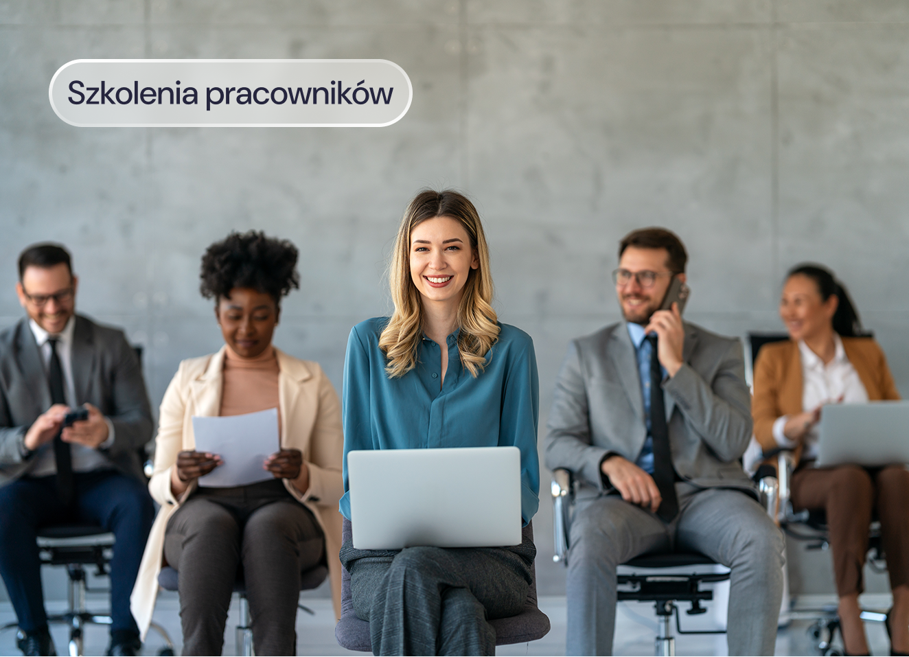 Uśmiechnięci pracownicy z laptopami na szkoleniu.