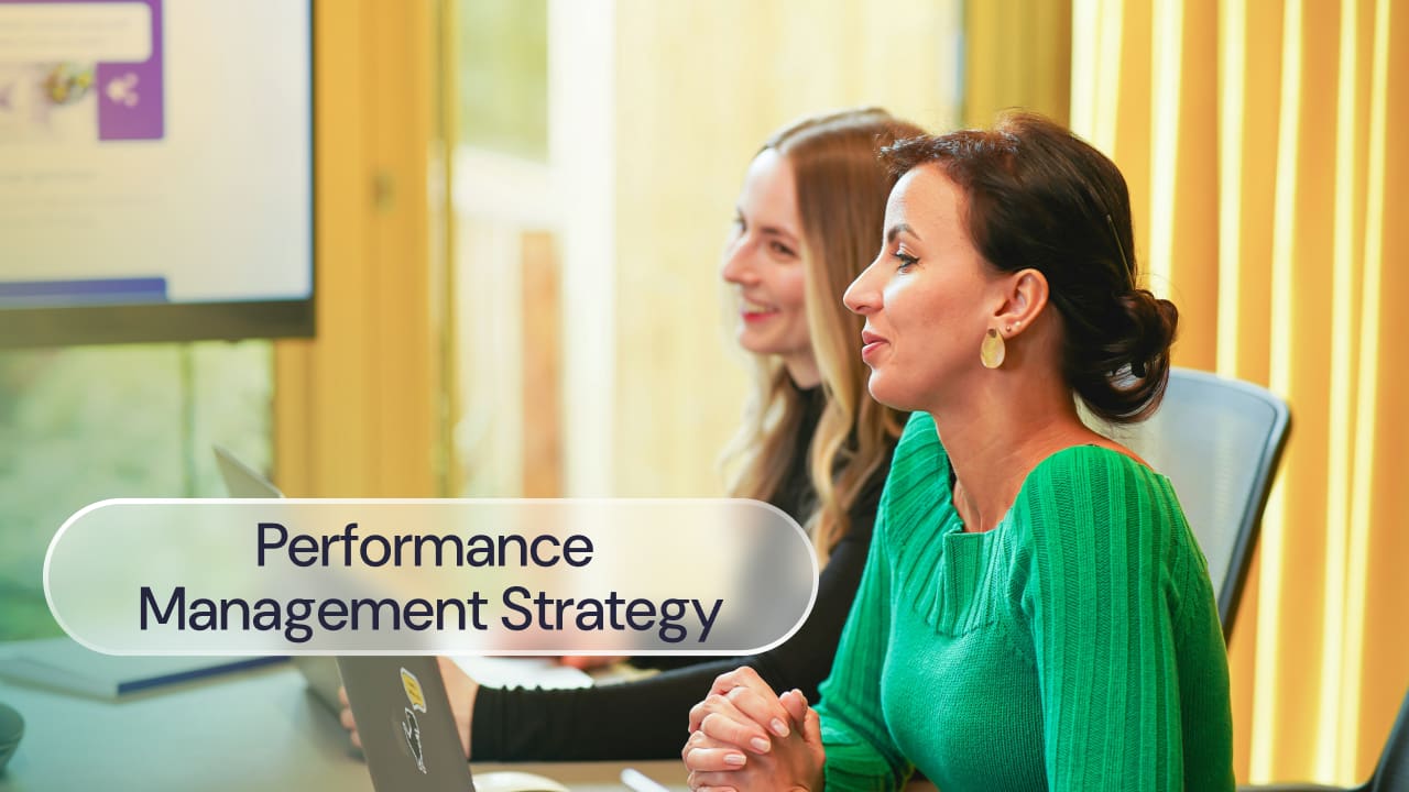 Two women at a desk in a meeting room, label reads: performance management strategy