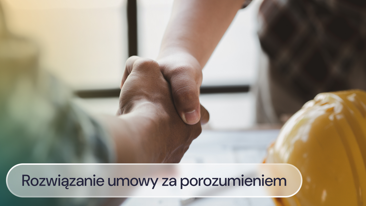 Dwie osoby ściskają sobie dłonie przy stole, na którym leży kask ochronny.
