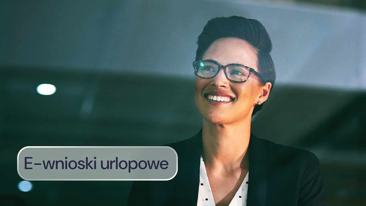 Uśmiechnięta kobieta w okularach w biurowym wnętrzu.