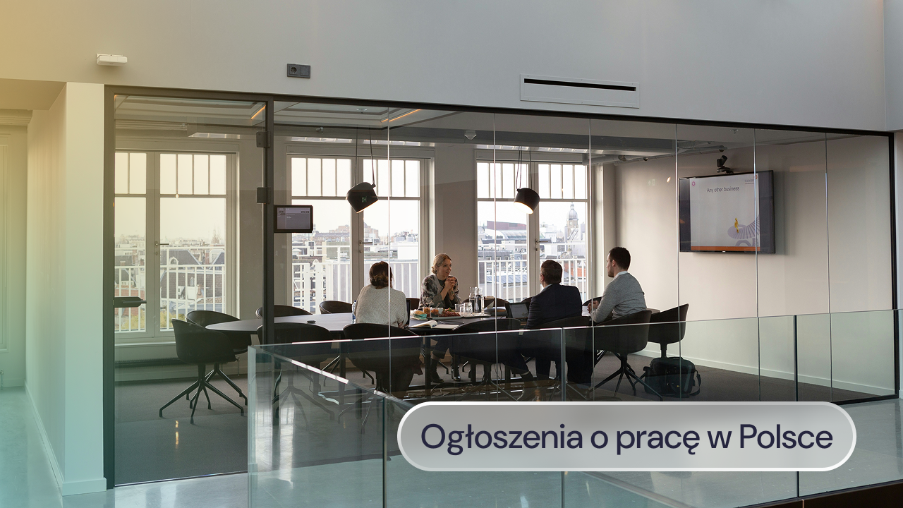 Pracownicy siedzą przy stole i pracują na laptopach.